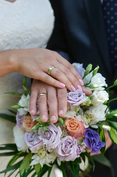 Mãos da noiva e noivo com anéis em um buquê de casamento — Fotografia de Stock