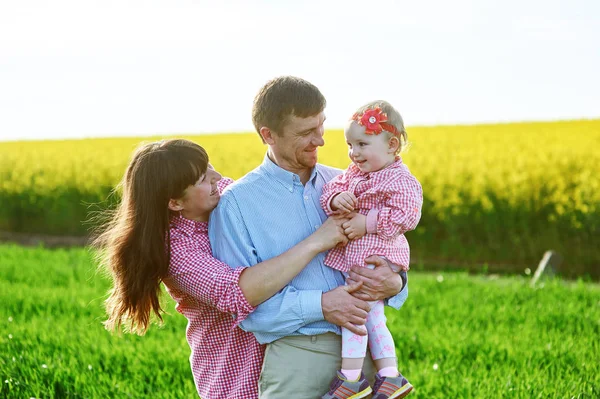 Mamá y papá y su hija están caminando en el campo verde de verano — Foto de Stock