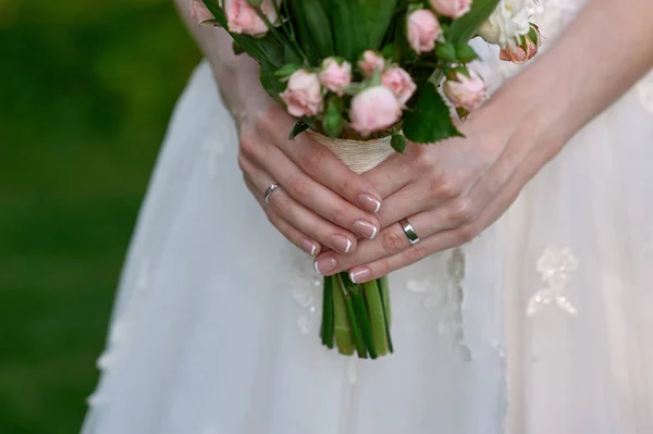 Hands of the bride with a gold ring hold a wedding bouquet — Stock Photo, Image
