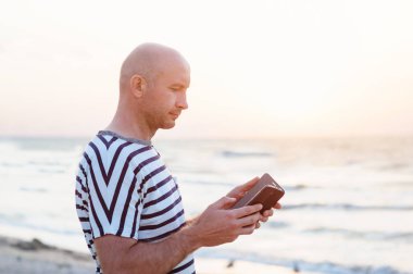 Deniz kıyısı telefonla adamla