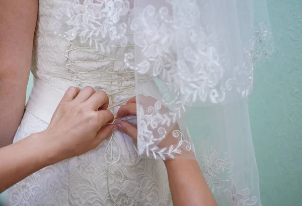 Bridesmaid helps to bride dress in wedding day — Stock Photo, Image