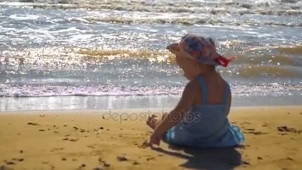 Kislány ül a homokos strandtól, és a homok festészet — Stock videók