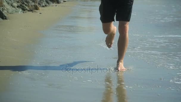 Man runs barefoot along the beach by the sea. Slow motion — Stock Video