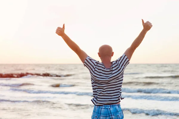 Szczęśliwy człowiek podnosi ręce przeciwko morza — Zdjęcie stockowe