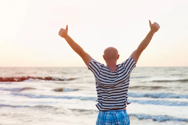 Glücklicher Mann hebt die Arme gegen das Meer — Stockfoto