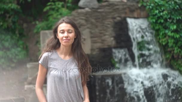 Mulher bonita posando contra um fundo cachoeira . — Vídeo de Stock