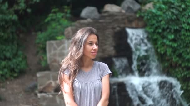 Mulher bonita posando contra um fundo cachoeira . — Vídeo de Stock