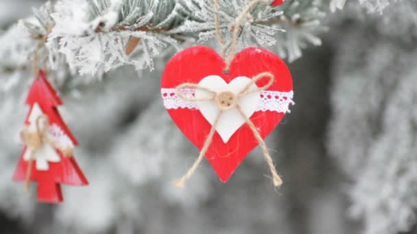 Brinquedos de Natal de madeira vermelha no abeto coberto de neve no parque de inverno — Vídeo de Stock