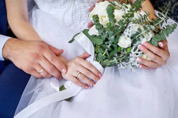 Noivo abraça a noiva com um buquê de casamento de flores para um passeio — Fotografia de Stock