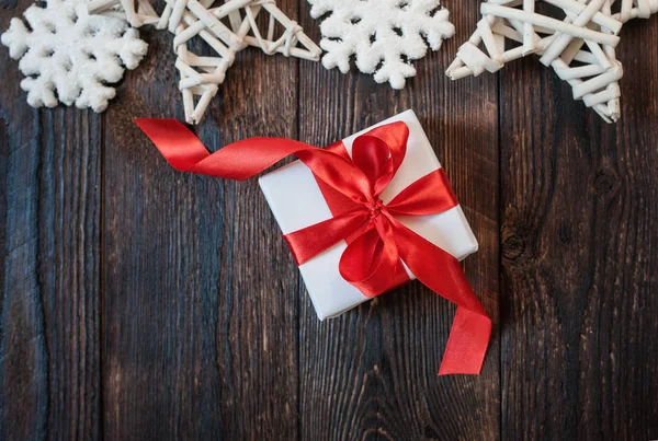 Gift box with red ribbon on a wooden background — Stock Photo, Image