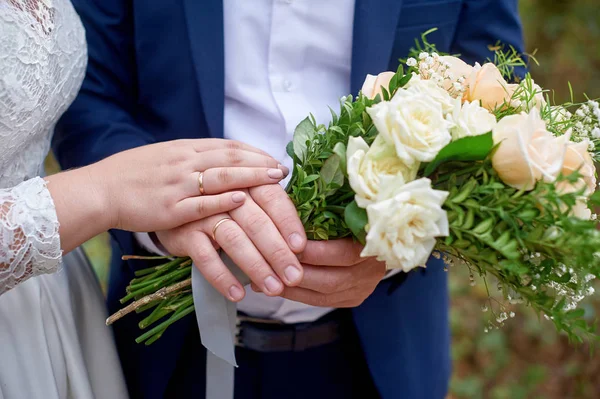 Bride put her hand on the bridegroom hand with the wedding bouquet — Stock Photo, Image