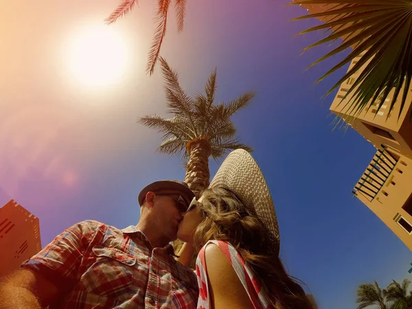 Pareja joven enamorada besándose sobre un fondo de palmera —  Fotos de Stock