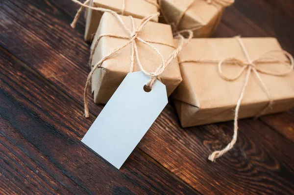 Коробки-макеты для подарков из крафтовой бумаги и подарочные бирки на деревянном фоне — стоковое фото