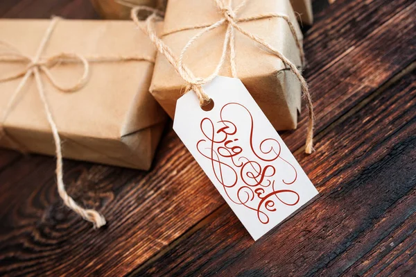 Twee geschenk dozen en label met grote verkoop tekst op kraftpapier en houten achtergrond. Handgeschreven kalligrafie en belettering — Stockfoto