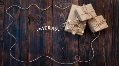 El beyaz Merry Christmas animasyon hat metin hediyeler ve tatil dekorasyon koyu ahşap zemin üzerine yazı yazma. Video tebrik kartı için. Mutlu duygu