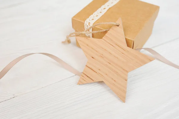 Natal etiqueta estrela de madeira com um presente no fundo de madeira branco. mockup para o seu texto — Fotografia de Stock