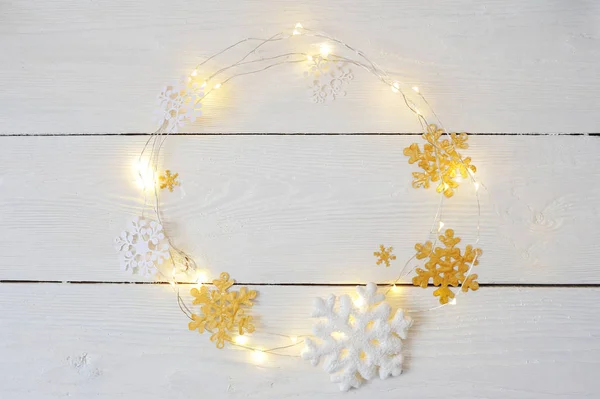 Corona de Navidad de copos de nieve y guirnaldas sobre un fondo de madera blanca —  Fotos de Stock