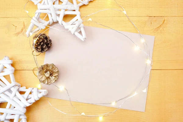 Natal fundo kraft folha de papel com lugar para o seu texto e estrela de Natal branco e guirlanda em um fundo de madeira dourada. Flat lay, vista superior foto mockup — Fotografia de Stock