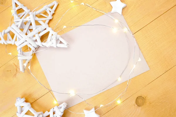 Natal fundo kraft folha de papel com lugar para o seu texto e estrela de Natal branco e guirlanda em um fundo de madeira dourada. Flat lay, vista superior foto mockup — Fotografia de Stock