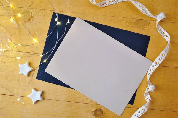 Vánoční pozadí kraft list papíru s místem pro text a bílá vánoční hvězda a věnečky na zlaté dřevěné pozadí. Plochá ležel, top view Foto maketa — Stock fotografie