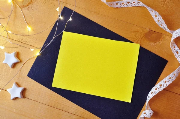 Feuille de papier jaune de fond de Noël avec place pour votre texte et étoile de Noël blanche et guirlande sur un fond en bois doré. Pose plate, top vue photo maquette — Photo