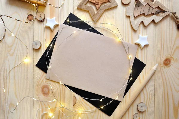 Foglio kraft sfondo di Natale di carta con posto per il testo e stella di Natale bianco e ghirlanda su sfondo di legno. Flat lay, vista dall'alto foto mockup — Foto Stock