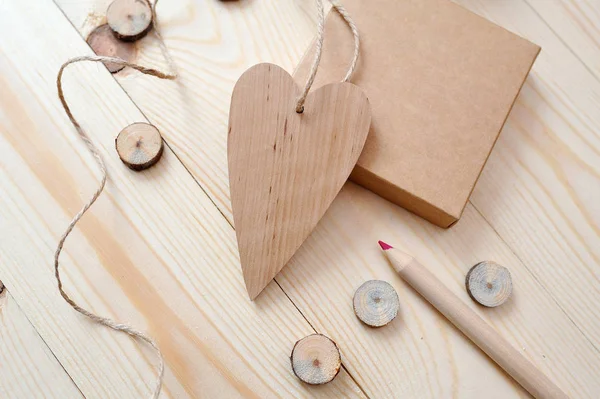 Boîte kraft et coeur en bois, courrier avec crayon sur un fond en bois. Pose plate, vue du dessus photo maquette — Photo