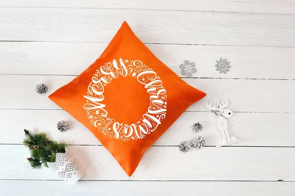 Texte Joyeux Noël sur un oreiller orange un fond de Noël en bois blanc. Pose plate, top vue photo maquette — Photo