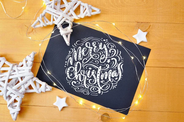 Texte Joyeux Noël sur un tableau noir avec étoile de noël deoccrusties, guirlande sur fond de bois doré. Pose plate, top vue photo maquette — Photo