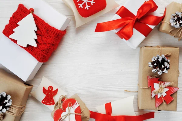 Coffrets de Noël cadeau décoré avec des arcs rouges sont disposés en cercle sur un fond en bois blanc. Pose plate, top vue photo maquette — Photo