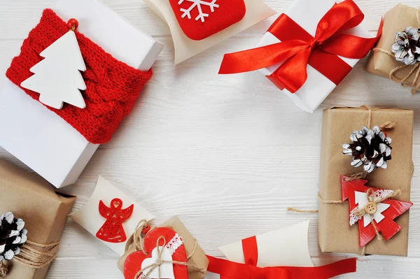 Christmas boxes gift decorated with red bows are arranged in a circle on a white wooden background. Flat lay, top view photo mockup — Stock Photo, Image