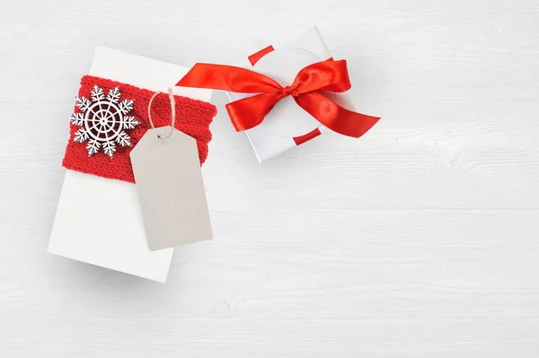 Makieta Christmas Gift Box i tag na drewniane tła z płatki śniegu, powitanie karta Wesołych Świąt i szczęśliwego nowego roku — Zdjęcie stockowe