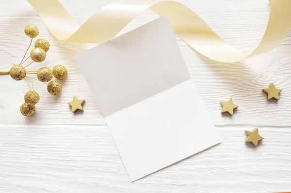 Mockup biglietto di auguri di Natale vista dall'alto e stella d'oro, flatlay su uno sfondo di legno bianco con un nastro, con posto per il testo — Foto Stock