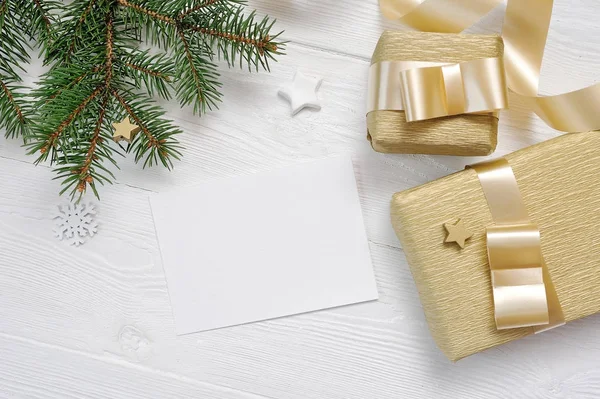 Mockup jul gratulationskort med träd och guld gåva band, flatlay på en vit trä bakgrund, med plats för text — Stockfoto