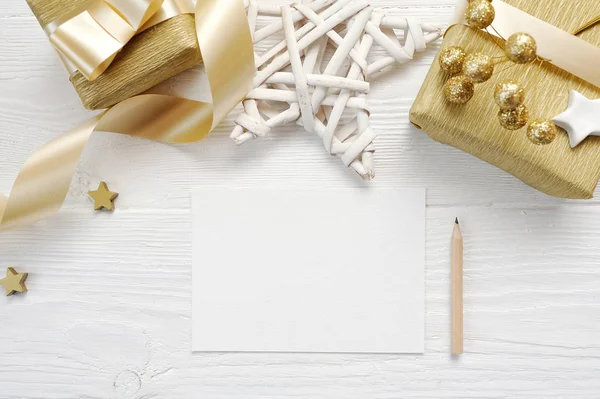 Mockup jul gratulationskort med guld gåva band, flatlay på en vit trä bakgrund, med plats för text — Stockfoto