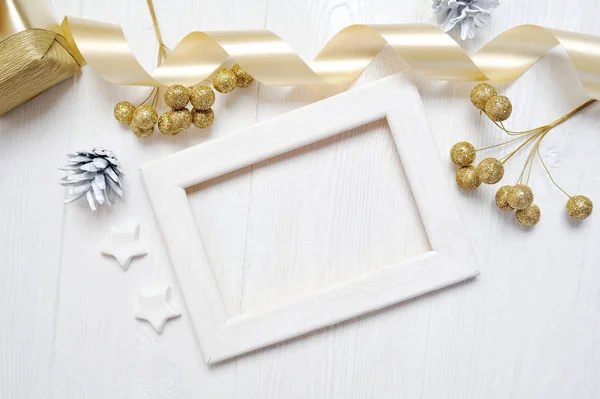 Mockup marco de madera de Navidad cinta de lazo de oro y cono de árbol, flatlay sobre un fondo de madera blanca, con lugar para su texto —  Fotos de Stock