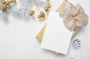 Mockup Noel Hediyelik altın yay ve ağaç koni, metniniz için yer ile beyaz ahşap zemin üzerinde flatlay