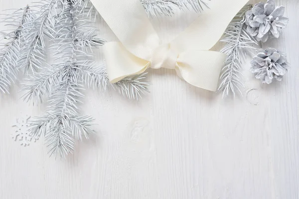 Макет рождественской белой елки и конуса, ленточный лук. Плоскость на белом деревянном фоне с местом для вашего текста — стоковое фото
