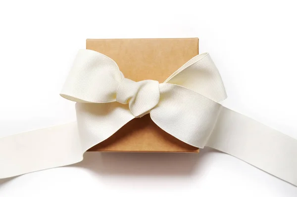 Holiday Gift box wrapped in brown recycled paper with white ribbon bow top view isolated on white background, top view — Stock Photo, Image