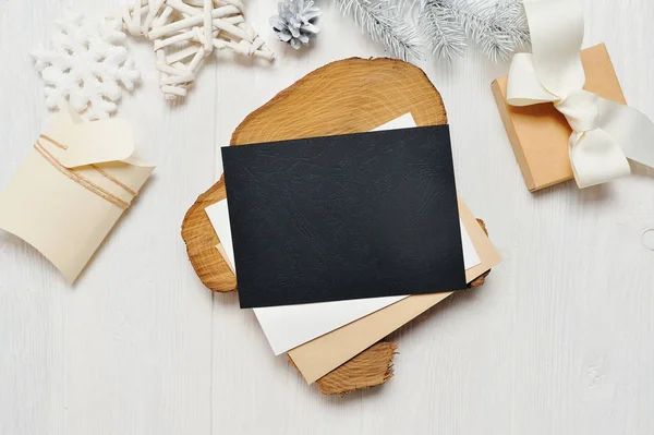 Mockup jul svart gratulationskort brev i kuvert och gåva med vita träd, flatlay på en vit trä bakgrund, med plats för text — Stockfoto