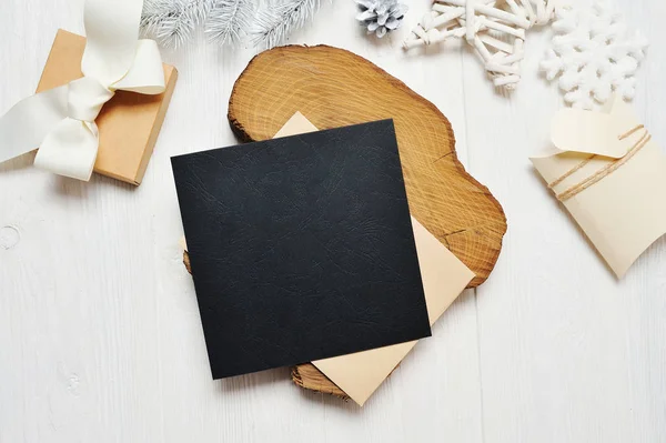 Mockup christmas black grußkarte brief in umschlag und geschenk mit weißem baum, flach auf weißem holzhintergrund, mit platz für ihren text — Stockfoto