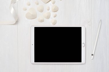 Mockup tablet bilgisayar ve kalp ile eski ahşap masa üzerinde kalem aşk, metniniz için yer ile beyaz ahşap zemin üzerinde flatlay. Düz yatıyordu, en iyi görünümü fotoğraf kadar sahte