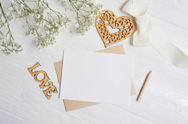 Bir aşk mektubu kadar sahte bir kalp şeklindeki kutu yatıyor gypsophila çiçekler ile ahşap bir beyaz masa, bir tebrik kartı Sevgililer günü için bir yer, metniniz için. Düz yatıyordu, en iyi görünümü fotoğraf