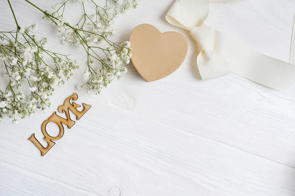 Kompozycja kwiaty makieta z gipsówki bieli dar z serca i napis miłość na białym tle drewnianych. Walentynki. Widok płaski świeckich, top z miejscem na Twój tekst — Zdjęcie stockowe