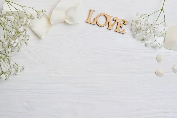 Mockup Flowers composition from a white gift gypsophila with a heart and an inscription Love on white wooden background. Valentines Day. Flat lay, top view with a place for your text — Stock Photo, Image