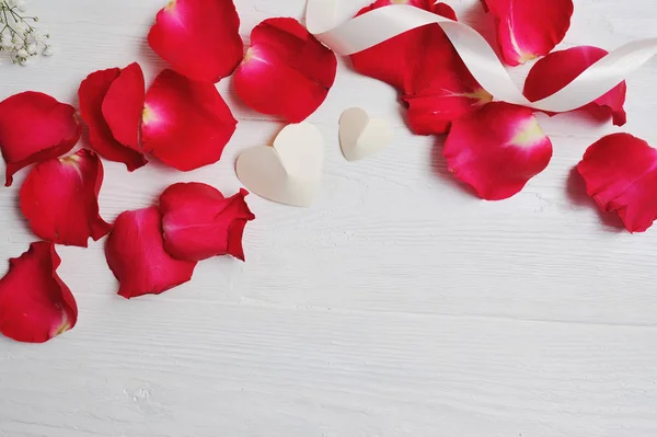 Mockup pétalos de rosa con dos corazones blancos sobre un fondo de madera blanca, tarjeta de San Valentín. Plano laico, vista superior con un lugar para su texto — Foto de Stock