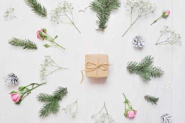 Χριστουγεννιάτικη σύνθεση κοροϊδεύω. Δώρο Χριστουγέννων, λουλούδια, κουκουνάρια, κλαδιά έλατου σε ξύλινο άσπρο φόντο. Επίπεδη lay, κορυφαία προβολή — Φωτογραφία Αρχείου