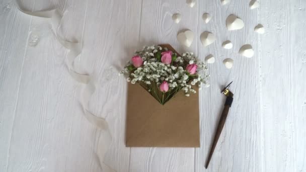 Kraft kuvert med blommor på en trä vit bakgrund med en kalligrafisk penna — Stockvideo