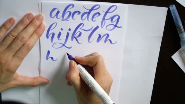 Motion video female hand writes a calligraphic alphabet in office — Stock Video