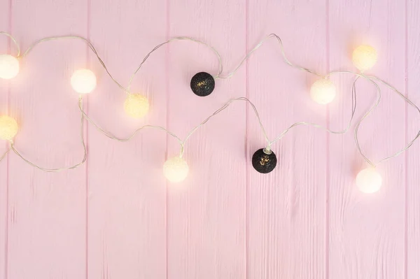 Weihnachtslichtergirlanden mit schwarz-weißen Kugeln umranden rosa Hintergrund. flache Lage, Kopierraum — Stockfoto